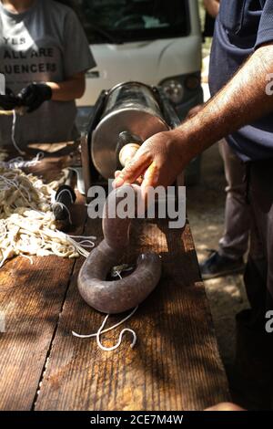 Hoher Winkel der Ernte anonymen Mann Füllung natürliche Wurst Gehäuse Mit frischem Hackfleisch in traditioneller lokaler Fabrik Stockfoto