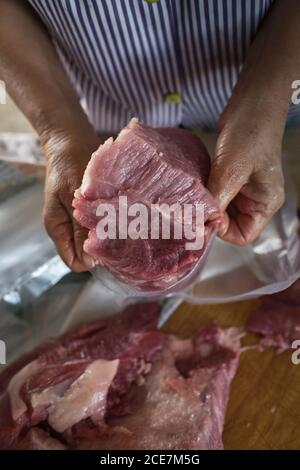 Von oben der Ernte anonyme Person, die Verpackung, schneiden das frische Fleisch Filet in Behältern während der Arbeit im Werk Stockfoto