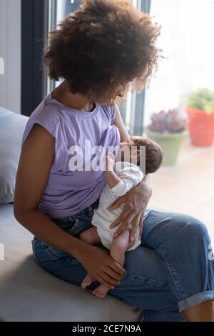 Inhalt African American weibliche Stillen Baby auf dem Sofa sitzen Zu Hause Stockfoto