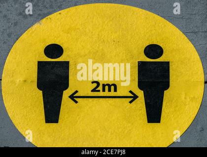 Halten Sie zwei Meter Abstand wegen Covid-19 Epidemie Zeichen auf Boden Stockfoto