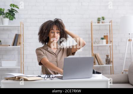 Probleme der Fernbildung. Schockierte Frau, die den Kopf hält und auf den Laptop schaut Stockfoto