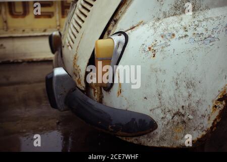 Nahaufnahme eines altmodischen Automobils mit gelbem Rücklicht und Schmutzige Oberfläche mit beschädigter Lackbeschichtung auf Asphaltstraße geparkt In der Stadt bei Tageslicht Stockfoto