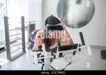 Frau trägt VR-Brille macht Übungen in einem Fitnessstudio Stockfoto