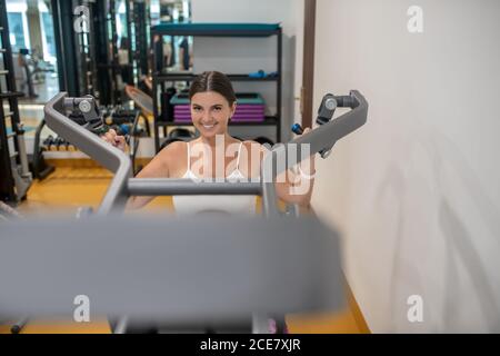 Lächelnde Frau, die ihre Hände in einer Turnhalle stärkt Stockfoto