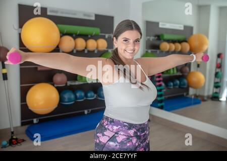 Plus-Größe Frau macht Übungen mit rosa Hanteln Stockfoto