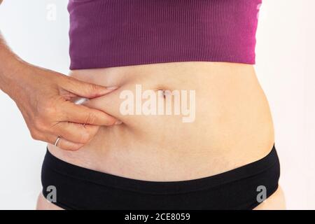 Reife Frau kneift ihren Bauch Fett, Körperpflege und Fitness-Konzept Stockfoto