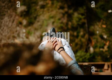 Von oben beschnitten unkenntlich Weibchen sitzen am Rand von alt Bauen und bewundern erstaunliche Landschaft im Sommer Stockfoto