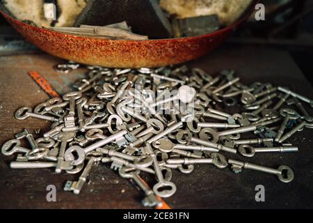 Haufen von verschiedenen Metallschlüsseln auf verwitterten Tisch in platziert Alte Werkstatt Stockfoto