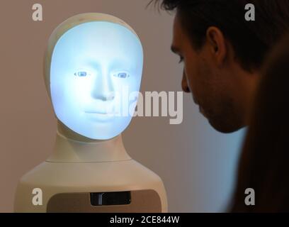 Darmstadt, Deutschland. August 2020. Patrick Schanowski, wissenschaftlicher Mitarbeiter, kommuniziert während einer Pressekonferenz an der TU Darmstadt mit dem Roboter 'Alfie', einer Moral Choice Machine. In Darmstadt soll ein Zentrum für Künstliche Intelligenz (KI) eingerichtet werden. Dafür stellt das Land Hessen in den nächsten fünf Jahren 38 Millionen Euro bereit. Das Zentrum wird in der Grundlagenforschung, aber auch in der Anwendung von KI involviert sein. Kredit: Arne Dedert/dpa/Alamy Live Nachrichten Stockfoto