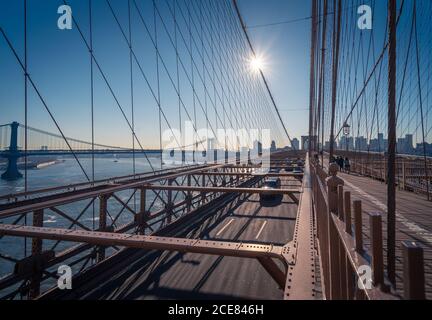 Autos fahren auf der berühmten Brooklyn Bridge über den Fluss in sonniger Lage Nachmittag in New York City Stockfoto