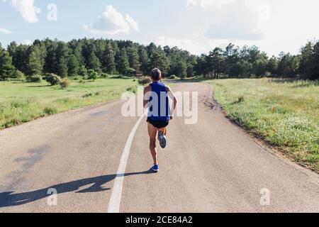 Entschlossener Mann, der während des Trainings auf der Straße läuft Stockfoto