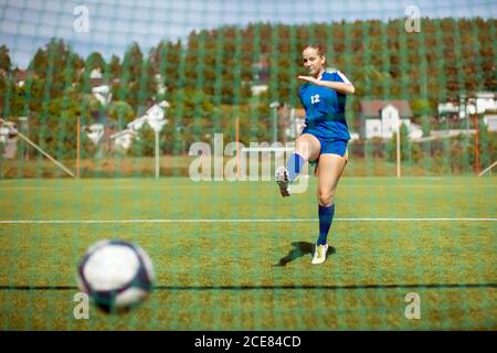 Weibliche Athletin schießen Ball ins Tor, während Fußball spielen auf Ein Stockfoto