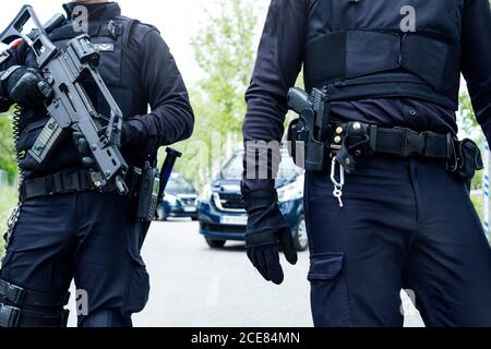 Ganzkörper-Trupp von spanischen Polizisten in Schutzausrüstung Mit Gewehren, die medizinische Masken tragen, während sie auf der Straße patrouillieren Stockfoto