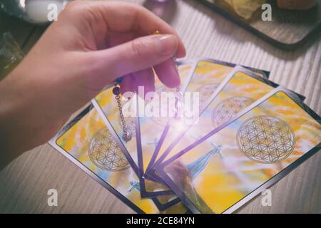 Tarot Karten wünschelrute Werkzeug in der Hand und Kristalle als ein Konzept der psychischen Advisor oder Möglichkeiten der Weissagung Stockfoto