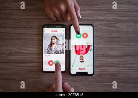 Draufsicht auf anonymen Mann und Frau drücken Like-Taste in Dating-App auf Smartphones auf Holztisch Stockfoto