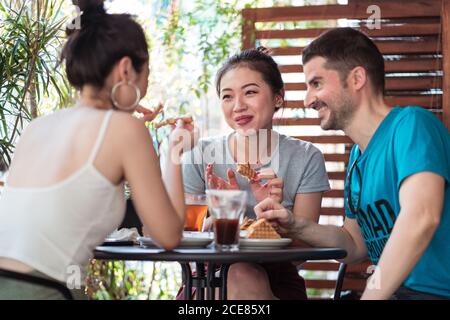 Fröhliche multiethnische Freunde, die im Café zu Mittag essen Stockfoto