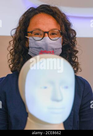 Darmstadt, Deutschland. August 2020. Angela Dorn (Bündnis 90/die Grünen), Wissenschaftsministerin des Landes Hessen, steht nach einer Pressekonferenz an der TU Darmstadt hinter dem Roboter 'Alfie', einer moralischen Wahlmaschine. In Darmstadt soll ein Zentrum für Künstliche Intelligenz (KI) eingerichtet werden. Dafür stellt das Land Hessen in den nächsten fünf Jahren 38 Millionen Euro bereit. Das Zentrum wird in der Grundlagenforschung, aber auch in der Anwendung von KI involviert sein. Kredit: Arne Dedert/dpa/Alamy Live Nachrichten Stockfoto