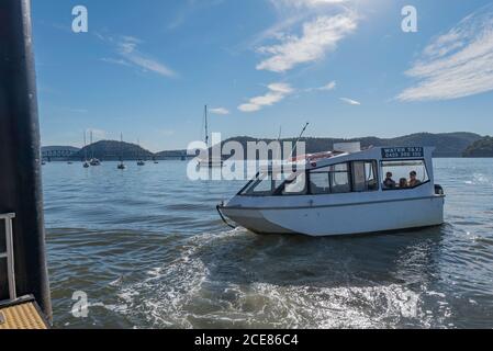 Ein Wassertaxi fährt von einem Kai auf Dangar Island ab, um eine Familie nach Brooklyn New South Wales, Australien, zu bringen Stockfoto