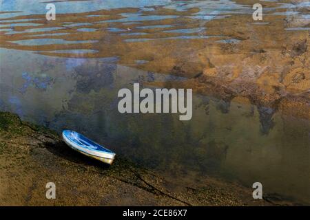 Ein Boot mit Strand vor Anker, während die Flut draußen ist Stockfoto