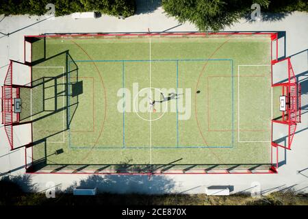 Von oben Drone Blick auf anonyme Sportlerin springen und werfen Ball während des Trainings auf Basketballplatz an sonnigen Tag Stockfoto