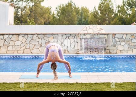 Nicht erkennbare weibliche stehend auf Yoga-Matte in Prasarita Padottanasana Pool im Hinterhof Stockfoto