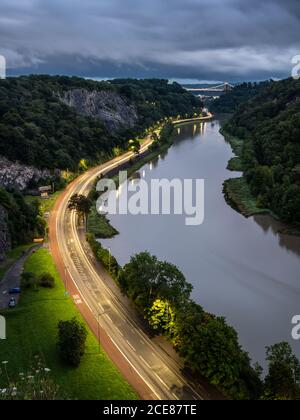 Der Verkehr hinterlässt in der Abenddämmerung auf der A4 Portway Road unter der Clifton Suspension Bridge in Bristol's River Avon Gorge. Stockfoto