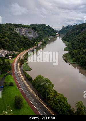 Der Verkehr hinterlässt in der Abenddämmerung auf der A4 Portway Road unter der Clifton Suspension Bridge in Bristol's River Avon Gorge. Stockfoto