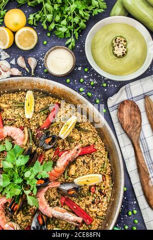 Draufsicht auf die Pfanne mit Arroz marinero garniert mit Zitrone Und Chilischoten mit Petersilie serviert auf dem Tisch mit Zutaten Stockfoto