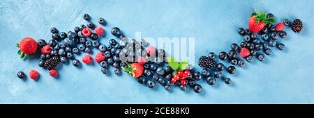 Ein veganes Panorama von frischen Sommerspeisen. Heidelbeeren, Himbeeren, Erdbeeren und rote Johannisbeeren, von oben geschossen Stockfoto