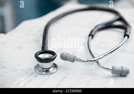 Von oben medizinisches Stethoskop mit Edelstahl und Kunststoff Teile auf Papierbogen, die das Kardiogramm mit welligen Linien darstellen Arztpraxis im Krankenhaus Stockfoto