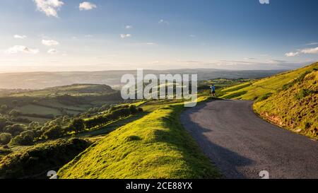 Ein Radfahrer beobachtet die Aussicht vom Gipfel der Gospel Pass Straße mit Blick auf das Wye Valley von den Black Mountains in Südwales. Stockfoto