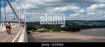 Radler überqueren die Severn-Mündung auf der alten Severn-Brücke, mit Beachley und Chepstow in der Ferne. Stockfoto