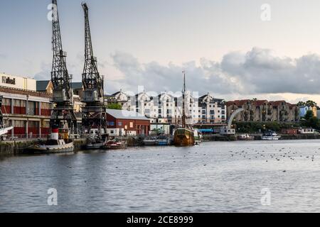 Das M Shed Museum, historische Schiffe und moderne Wohngebäude auf der regenerierten post-industriellen Hafenseite von Bristol werden abends beleuchtet. Stockfoto