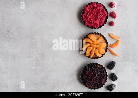 Draufsicht auf schmackhafte Kuchen mit verschiedenen reifen Früchten und Beeren in der Reihe auf dem Tisch angeordnet Stockfoto