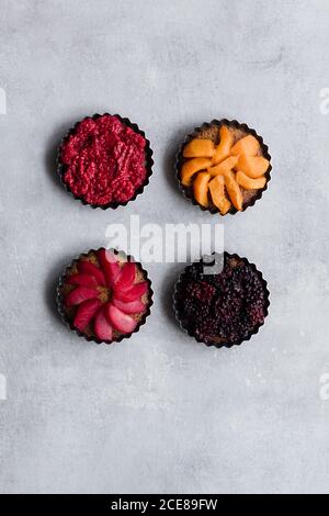 Draufsicht auf schmackhafte Kuchen mit verschiedenen reifen Früchten und Beeren auf dem Tisch arrangieren Stockfoto