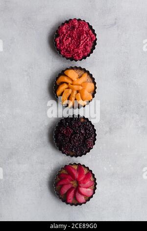 Draufsicht auf schmackhafte Kuchen mit verschiedenen reifen Früchten und Beeren in der Reihe auf dem Tisch angeordnet Stockfoto