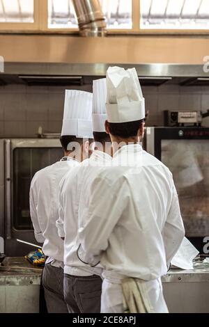 Rückansicht anonymer Männer in Uniform, die in der Moderne arbeiten Küche des Luxusrestaurants Stockfoto