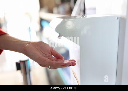 Frau Hand bringt es automatische antiseptische Spender Stockfoto