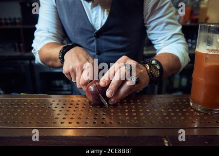 Cropped unkenntlich professionellen Barkeeper schneiden Passionsfrucht mit Messer während Einen Cocktail in der Bar zubereiten Stockfoto