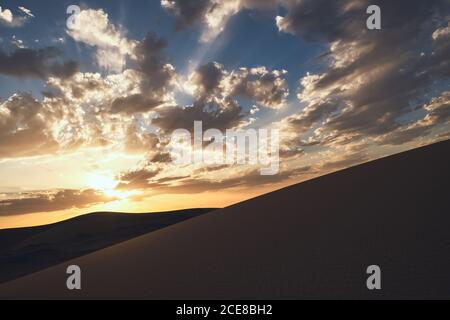 Minimalistische Wüstenlandschaft mit Sanddünen und schönem Sonnenuntergang mit blauem Himmel in Hami, Xinjiang in China Stockfoto