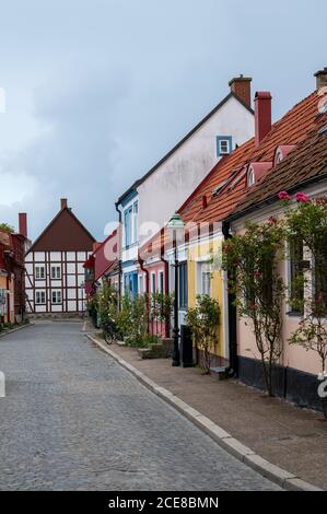 Eine leere gemütliche gepflasterte Straße mit bunten Stadthäusern und Hütten im Dorf Ystad, Schweden Stockfoto