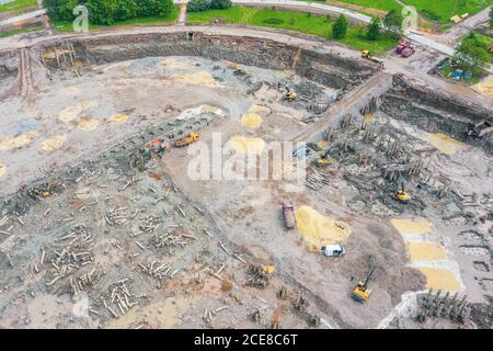 Arbeitsbagger auf dem Gelände eines abgerissenen Gebäudes. Verladung von Zementrückständen in die Zerkleinerungsanlage und den LKW-Boden, Draufsicht Stockfoto