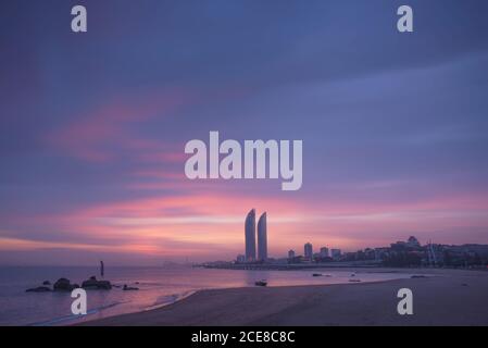 Silhouetten moderner Wolkenkratzer am Meer der Stadt Xiamen Gegen bunten Sonnenuntergang Himmel in der Abendzeit in China Stockfoto