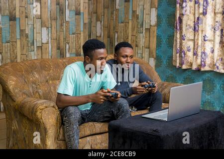 Afrikanische Männer spielen ein Videospiel auf einem Laptop bei Zu Hause Stockfoto