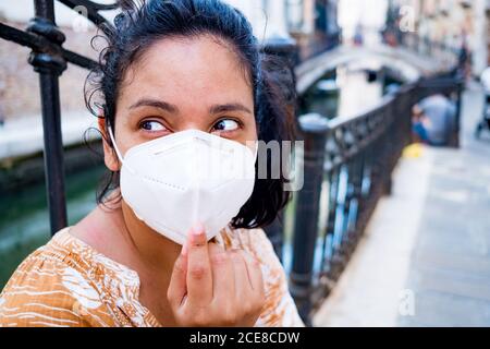 Junge Frau mit OP-Maske sitzt in einer Straße von Venedig in Italien. Reisen und Tourismus-Industrie während der Coronavirus-Pandemie und covid19 viru Stockfoto