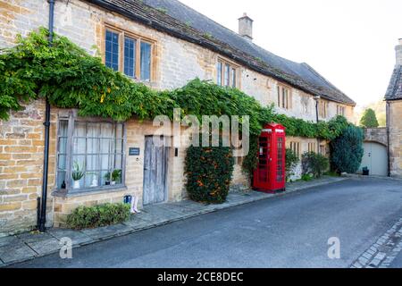 Ein Reethaus aus lokalem Schinkenstein und einer historischen roten Telefondose im Zentrum von Montacute Village, Somerset, England, Großbritannien Stockfoto