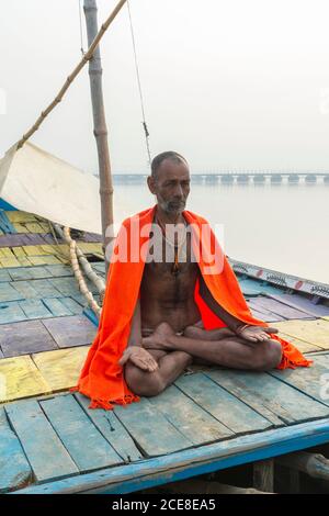 Sadhu mit rotem Schal auf einer Bootsfahrt auf dem Ganges bei Sonnenaufgang, Allahabad Kumbh Mela, der weltweit größte religiöse Versammlung, Uttar Pradesh, Indien Stockfoto