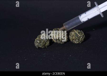 Nahaufnahme von Teebällen und einer Spritze auf einem Schwarze Oberfläche Stockfoto