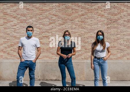 Drei Freunde im Freien tragen Gesichtsmasken und respektieren soziale Distanzierung Während einer Pandemie Stockfoto