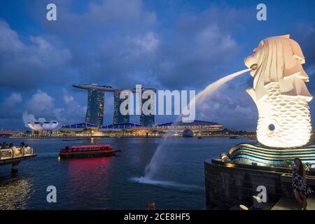 Singapur, der Merlion, Statue, die ein mythisches Wesen mit einem Löwenkopf und dem Körper eines Fisches darstellt, in Marina Bay. Im Hintergrund die Marina Stockfoto